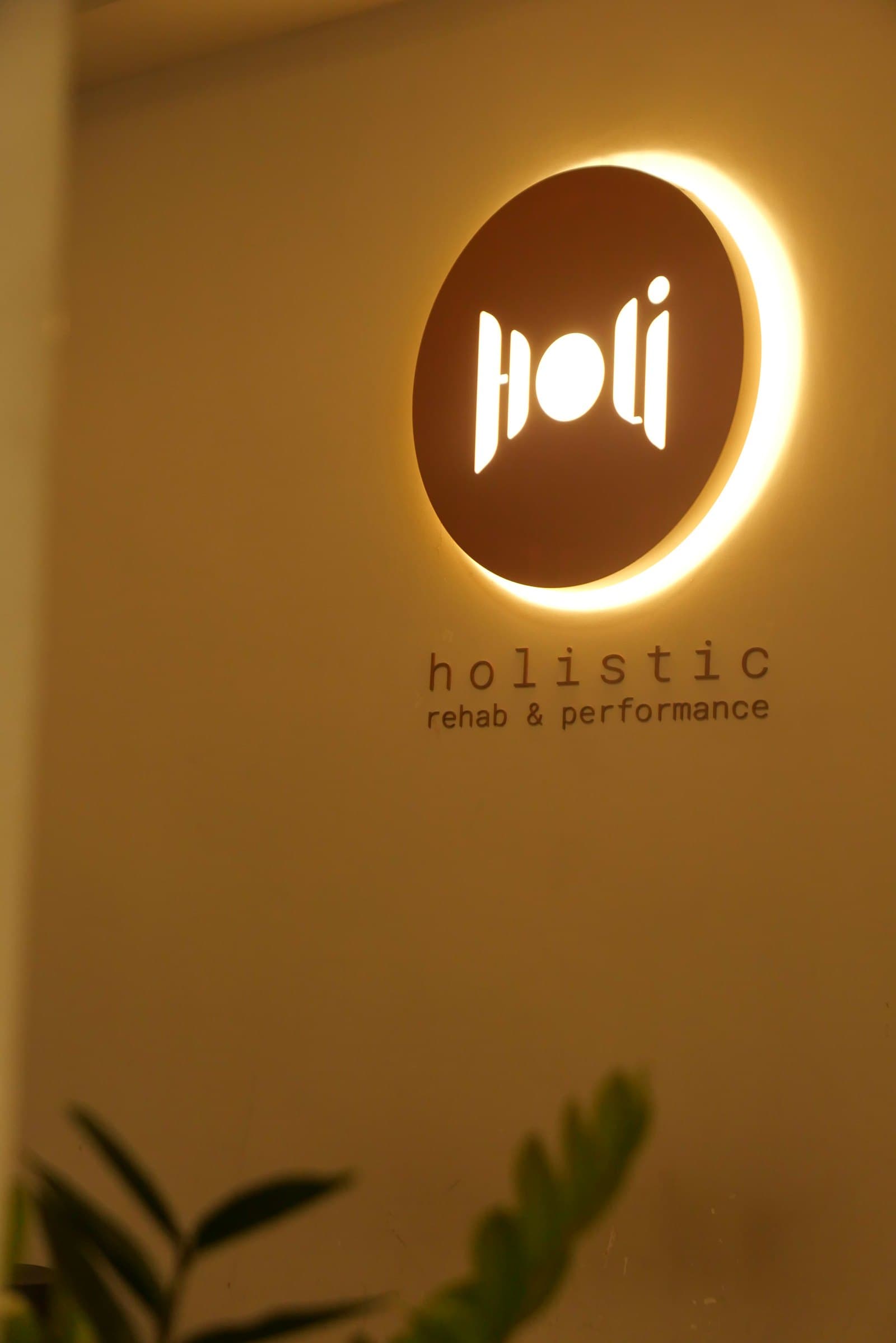 Bảng hiệu Holistic rehab & performance phát sáng trong phòng trị liệu